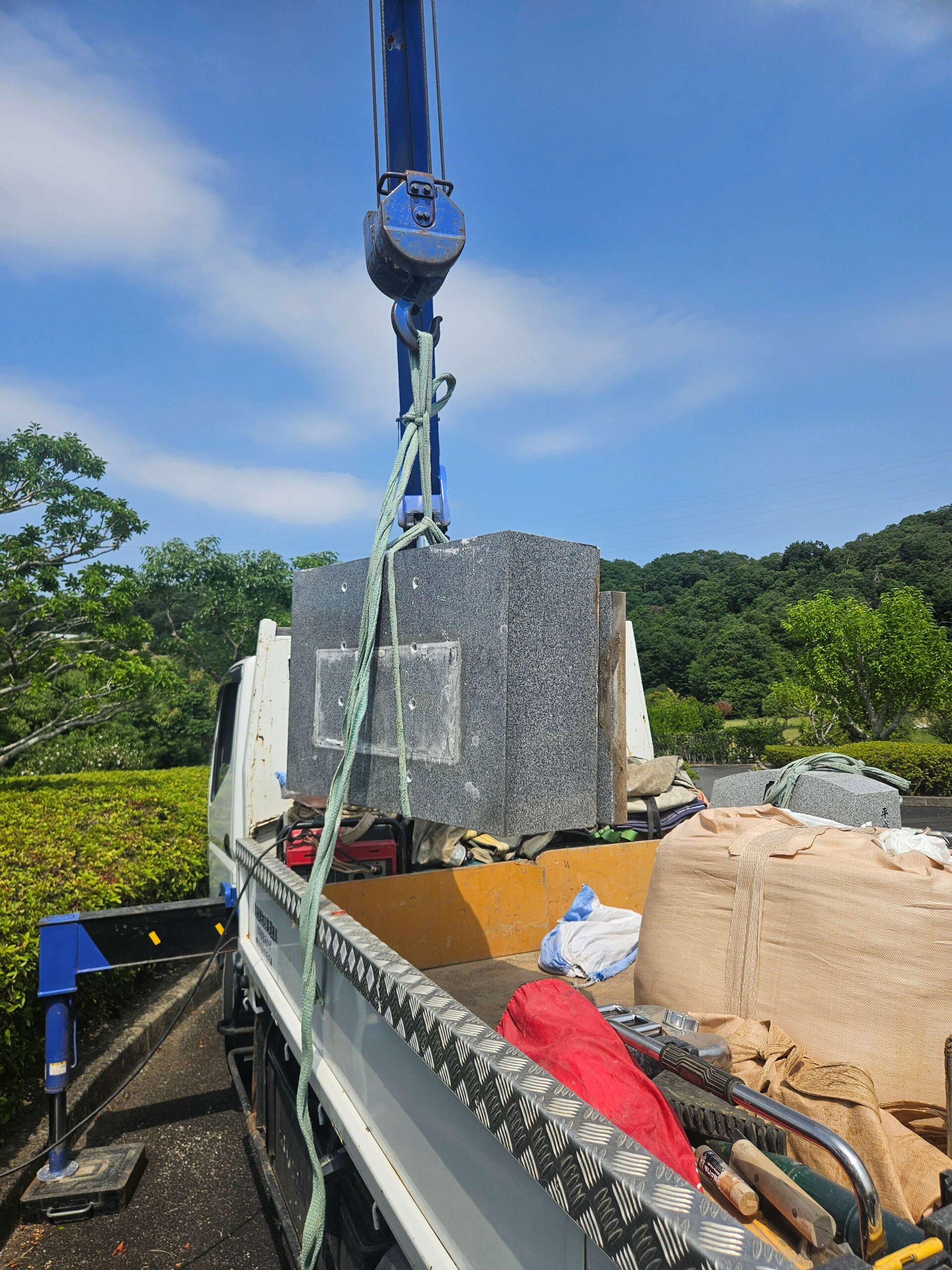 飯盛霊園の解体・墓石撤去作業で搬出用トラックへ資材を積み込む風景